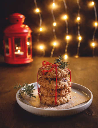 healthy oatmeal cookies with dried berries on a background of a burning garland. Homemade baking. festive christmas atmosphereの写真素材