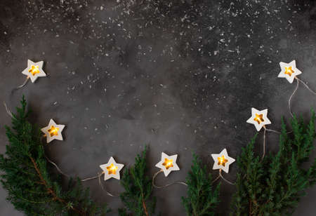Christmas or New Year concept frame with winter holiday decorations. dark background with a burning garland. copy space.の写真素材