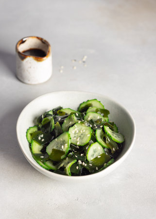 bowl with wakame seaweed cucumber salad on gray background.