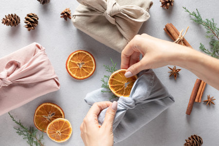 female hands packing gifts in linen cloth. Furoshiki gifts.