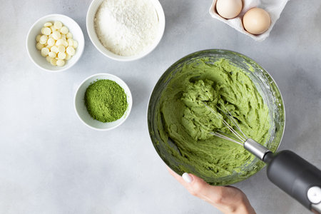 female hands mixing dough with mixer in bowl