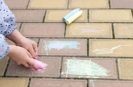 little girl hands draws on asphalt, paving stonesの写真素材