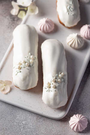 delicious eclairs with glaze and sugar sprinkles on white plateの写真素材