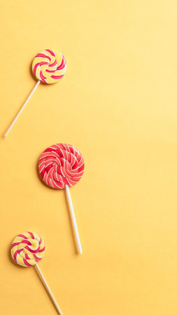 colorful round lollipops on yellow background. Festive background. banner, flat lay, empty space for...