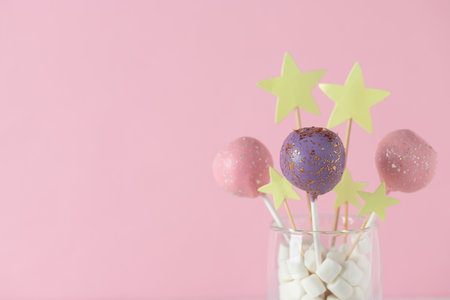 delicious cake pops in a glass jar on a pink background. festive background. horizontal image. copy...