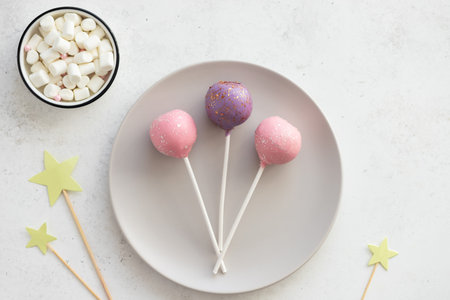 Three sweet cake pops on a plate on a white background. dessert for kids party. horizontal image....