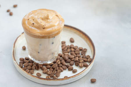cold Dalgona coffee with whipped cream in a glass on a background of coffee beans. summer ice drinks. close-up. horizontal image. copy spaceの写真素材