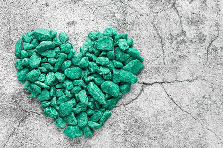 heart shape made of turquoise decorative stones on a gray surface with cracks. Love, passion, feelings concept. minimalism. top view. horizontal imageの写真素材