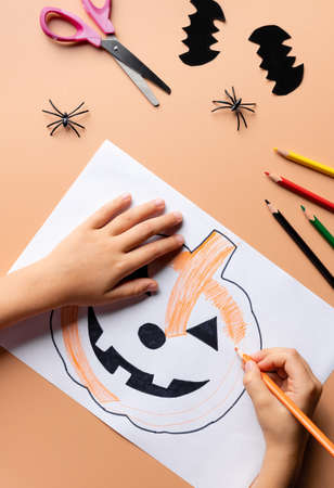 child drawing scary pumpkin on white paper. DIY craftの写真素材