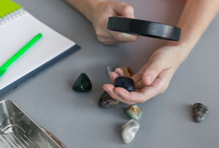 boy studying semiprecious stones with magnifying glass at lessonの写真素材