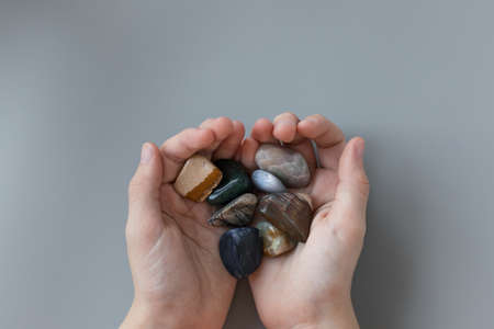 child holding various semiprecious stones in hands on gray backgroundの写真素材