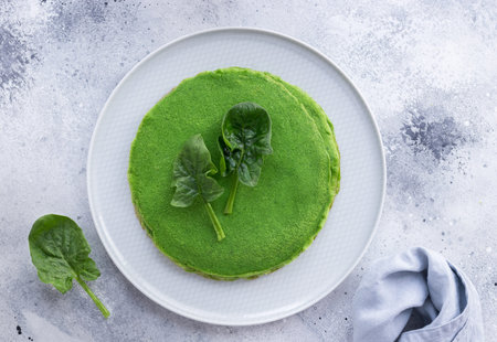 Green crepes with spinach on gray background. Vegan alternative food. top view
