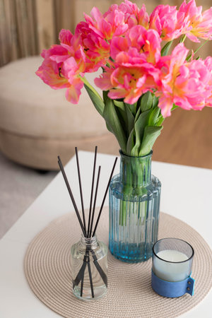 aroma reed diffuser, tulips in vase and candle on table at home. Aromatherapy, home fragrance....