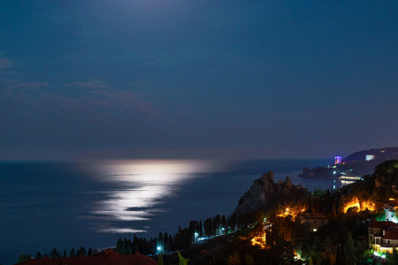 night view of seashore city with calm blue sea and shiny reflections on water. relax and vacation conceptの写真素材