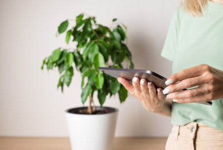 woman in living room using digital tablet touchpad for reading, online shopping, scrolling on social...