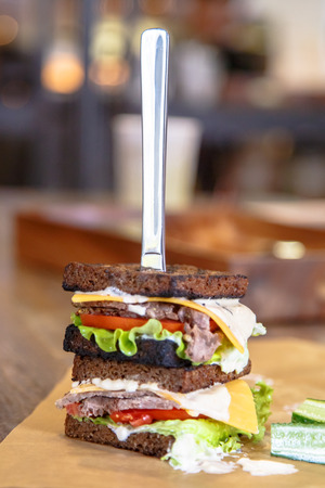 A sandwich with meat, vegetables, salad and cheese on the table.の写真素材