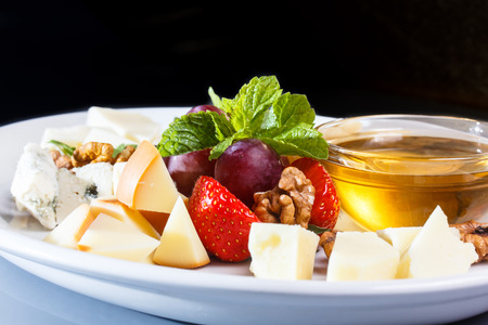 A plate of different cheeses and berries.の写真素材