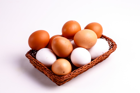 Brown and white chicken eggs lying in a wicker basket.の写真素材