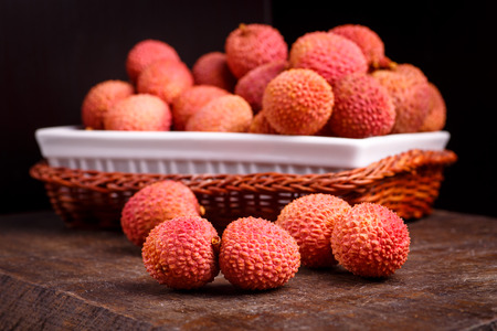 Lychee fruit, which is called Chinese plum, is on the dark Board and in basket.の写真素材