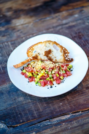 Salmon tartare with avocado on toasted bread is on the saw cut of a log.の写真素材