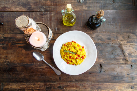 Risotto with red bell peppers is the plate on the old table.の写真素材