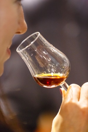 Liqueur or other hard drink in the glass "Tulip" in the hand of the manの写真素材