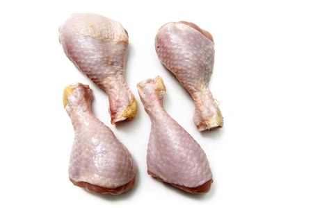 Raw Chicken drumstick rests on a white background.の写真素材