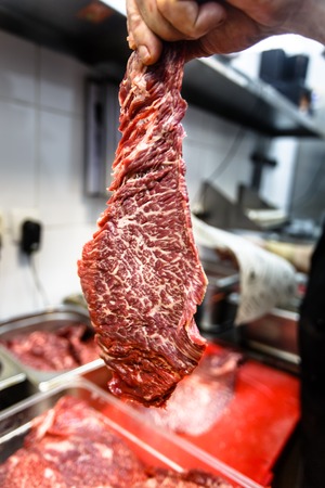 Raw steak "skirt", "butcher's steak" or "Machete" in the hands of the seller or butcher.の写真素材