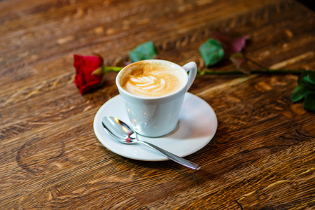 The cappuccino Cup is on the table. Nearby is the rose.の写真素材