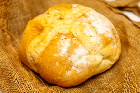 Homemade round bread from wheat flour lies on rough cloth..