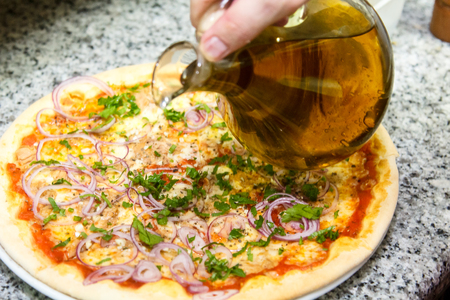 Pizza cooking. The cook pours the cooked pizza with olive oil.の写真素材