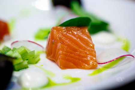 Slice salted salmon is on the plate of cucumber and radish. Macro.の写真素材