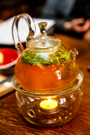 Tea in a glass teapot on a stand with a candle.の写真素材