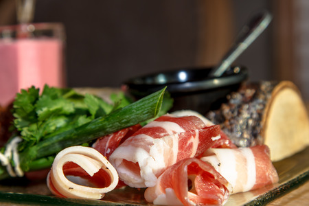 Bacon (Salo) with streaks of meat with onion and parsley lying on a glass plate. As decoration used a birch log - a hint of Russian cuisine.の写真素材