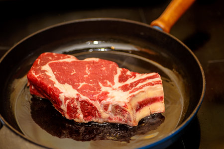 Raw beef loin on the bone (marble), fried in a skillet.の写真素材