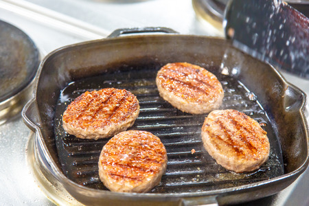 Beef burgers are fried on a frying pan grill.の写真素材