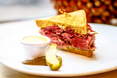 Sandwich with pastrami, cucumber and sauce is on the plate.の写真素材