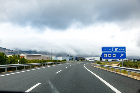 Road in the fog with a pointer to the gas station and Parking.の写真素材