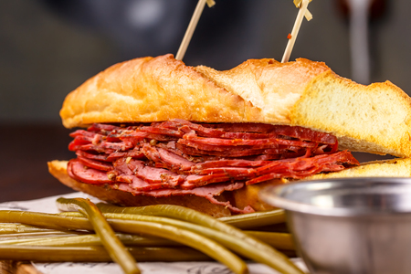 Sandwich pastrami on a sheet of paper lies on the Boardの写真素材