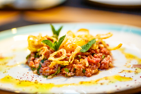 Beef tartare with fried onion lies on the plate.の写真素材