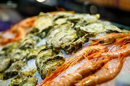 Shrimp and oysters lying on ice in the window.の写真素材