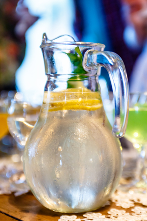 The glass carafe of lemonade from lemons with mint is on the table.の写真素材