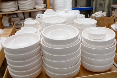 A pottery. white bowls and plates are on shelves of the cupboard