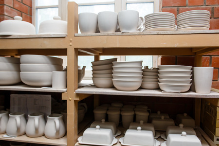 A pottery. white bowls and plates are on shelves of the cupboardの写真素材