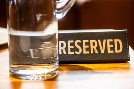 Black sign "reserved" on the table at the restaurant in a carafe of waterの写真素材