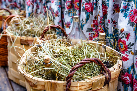 Bottles of alcohol lie in a basket with hayの写真素材