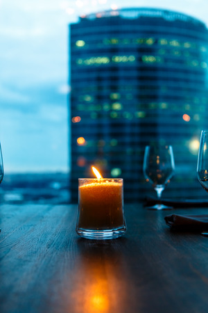 Burning candle and glasses in the evening on the restaurant table.の写真素材
