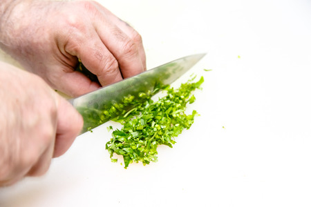 Cook cuts parsley on a white Boardの写真素材