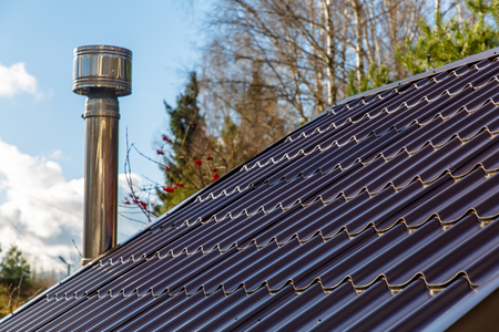 The roof of the house with a pipe on the background of yellow treesの写真素材