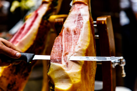 The seller cuts Spanish ham with a thin long knife